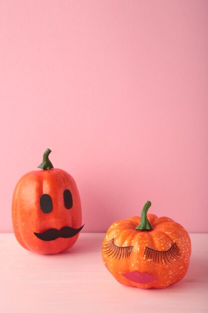 Calabaza de Halloween con maquillaje en rosa. Fondo de concepto de temporada de vacaciones mínima. Hombre y mujer. Foto vertical