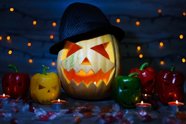 Calabaza de Halloween con sombrero, pimientos coloridos brillantes de miedo, velas, caramelos, dulces