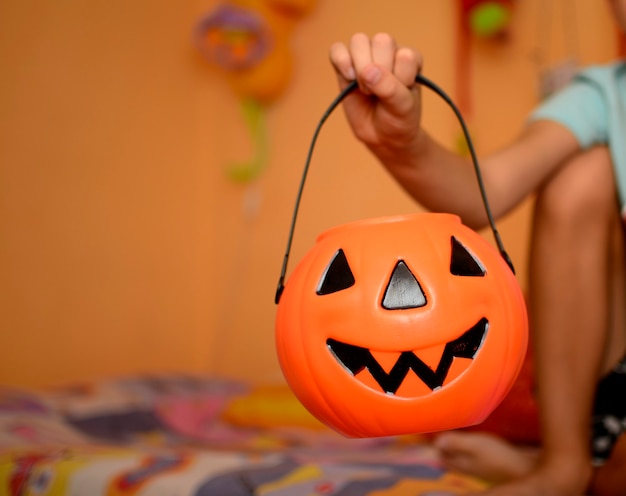 Calabaza de Halloween sosteniendo en la mano del niño caja de dulces de truco o trato