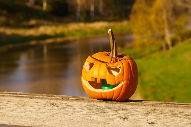 Calabaza de Halloween tallada con paisaje borroso en el fondo.