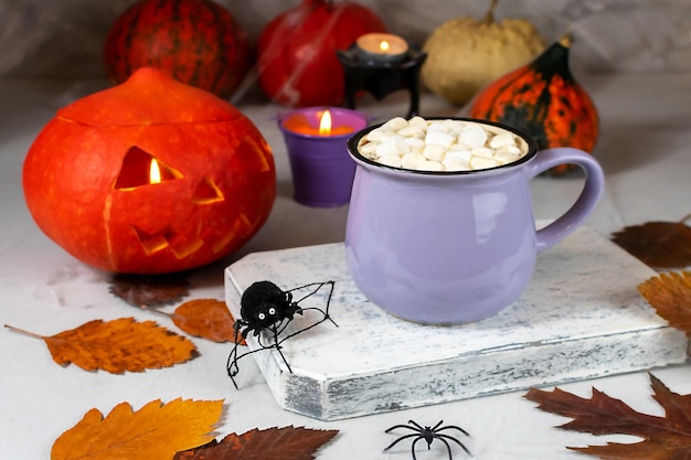 Calabaza de Halloween y taza de café con galletas con arañas, velas, calabazas, hojas.