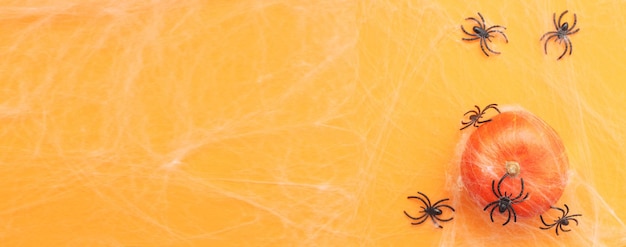 Calabaza de Halloween con telaraña y arañas negras sobre fondo naranja