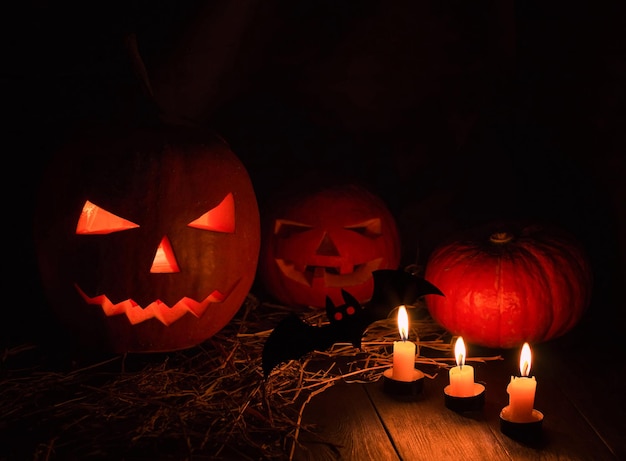 Calabaza de Helloween con velas y murciélagos sobre fondo negro. Gran símbolo espeluznante de helloween