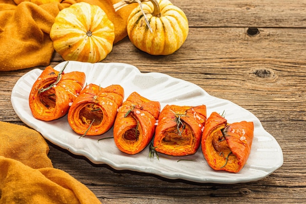 Calabaza Hokkaido al horno con salsa especias y miel Comida vegana saludable romero seco moderno luz dura sombra oscura Fondo de hormigón de piedra negra espacio de copia