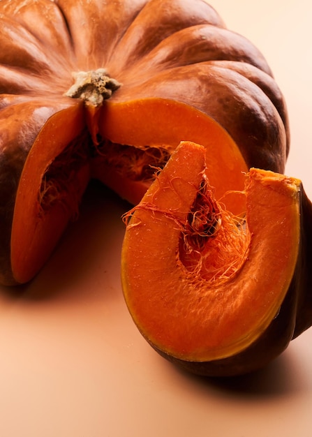 Calabaza madura en rodajas cerca de fondo naranja