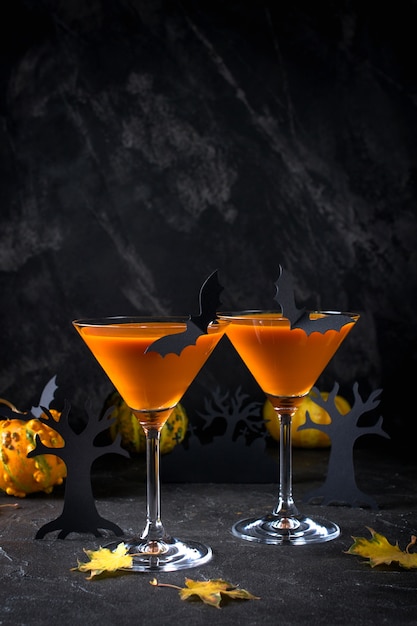 Calabaza naranja, bebida de Halloween para fiestas y decoraciones navideñas sobre fondo negro con espacio de copia