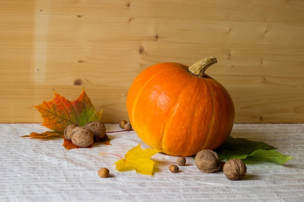 Calabaza nueces avellanas y hojas de otoño sobre la mesa