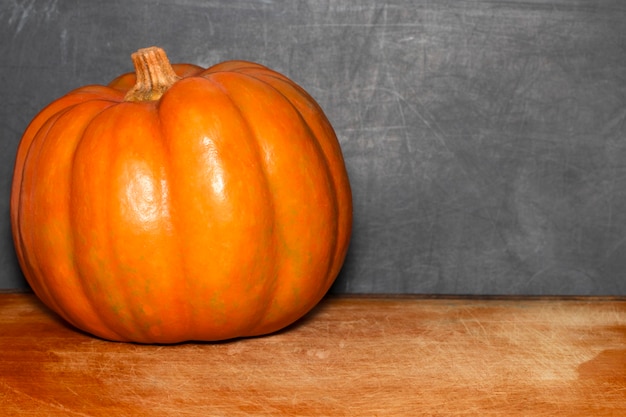 Calabaza de otoño en la mesa del aula frente a una pizarra.