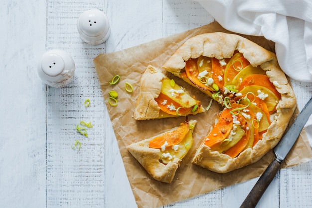 Calabaza, patata, queso feta y plato de pastel de galette de puerro sobre la superficie de la mesa de madera blanca. Vista superior.