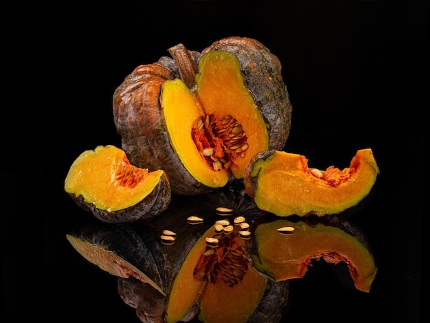 Calabaza con rodajas y semillas en vidrio negro con reflejo