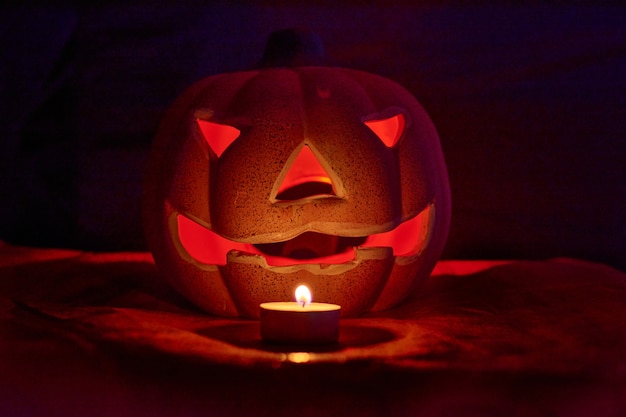 Una calabaza tallada iluminada y una vela en un fondo oscuro - concepto de halloween