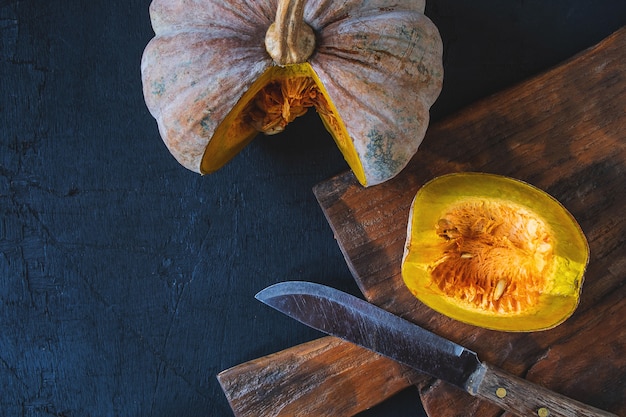 Calabaza vegetal cortada por la mitad en una tabla de cortar de madera