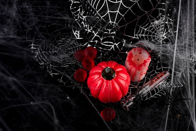 Calabaza, vela y un vaso largo con un cóctel rojo.