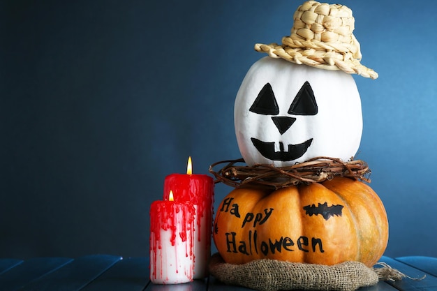 Calabazas blancas de Halloween y velas en la mesa de madera sobre fondo de color oscuro