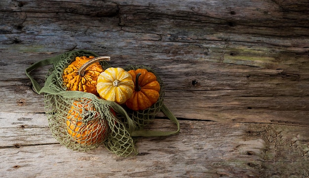 Calabazas en una bolsa de hilo de embalaje alternativa en una vista superior de fondo de madera