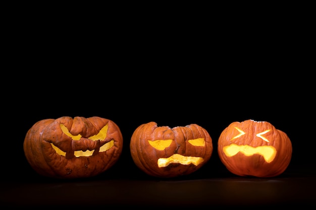 Calabazas de halloween con expresiones terrorificas y fondo de luces