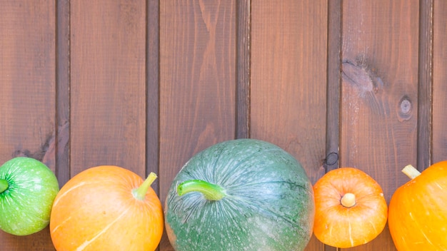 Calabazas de diferentes colores y tamaños sobre un fondo de madera