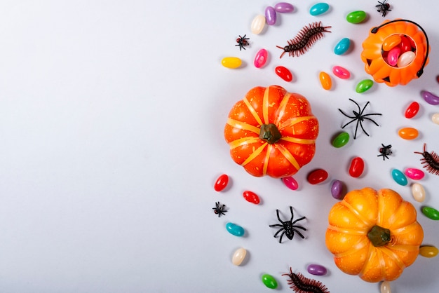 Calabazas y dulces esparcidos en gris.