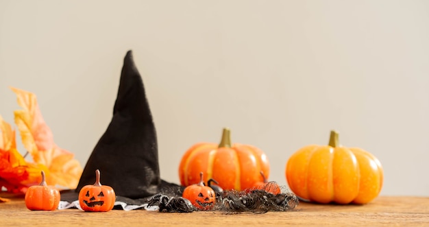 Calabazas espeluznantes de color naranja con araña y sombrero de bruja y hojas de arce para el concepto de halloween