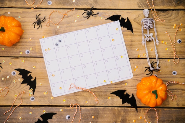 Calabazas esqueletos arañas y murciélagos sobre un fondo de madera Calendario o horario Un tema festivo de Halloween Espacio vacío para texto