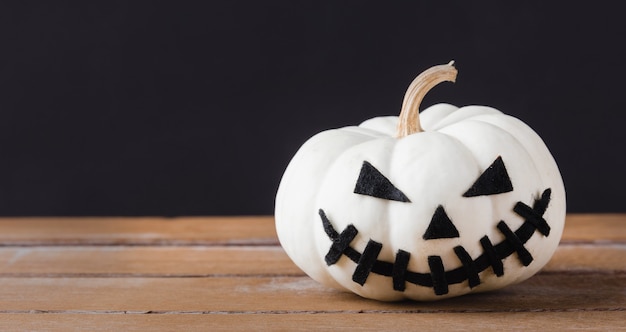 Calabazas fantasma cabeza jack lantern sonrisa de miedo en la mesa de madera