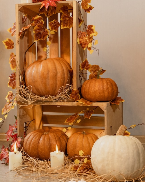 Calabazas de Halloween en las cajas de madera con velas, paja, hojas de otoño