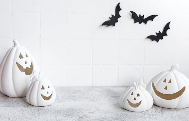 Calabazas de Halloween y decoración de jack o lantern contra una pared blanca con murciélagos.