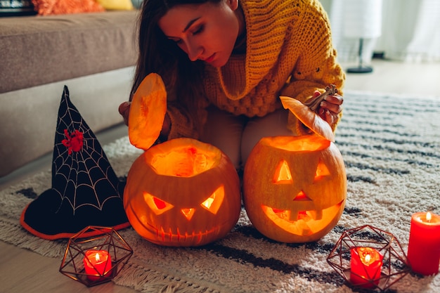 Calabazas de Halloween Jack-o-Lantern, mujer abre calabazas y mira dentro de casa