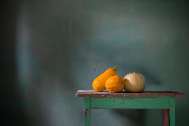 Calabazas naranjas en la mesa de madera vieja en la pared verde de fondo