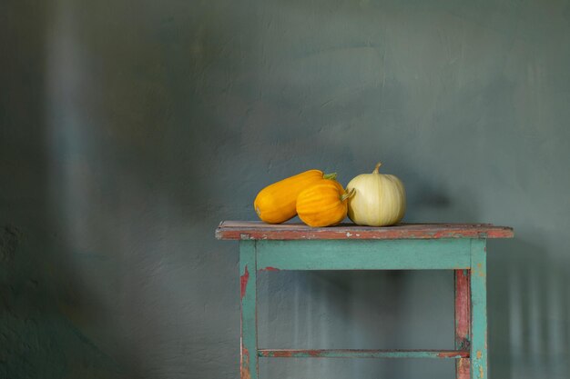 Calabazas naranjas en la mesa de madera vieja en la pared verde de fondo