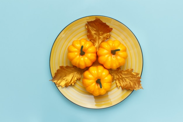 Calabazas en un plato amarillo sobre turquesa pastel.