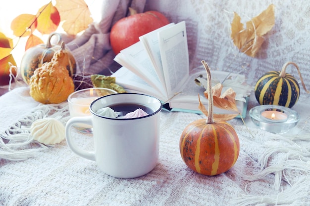 Calabazas una taza de café hojas de otoño velas encendidas y un libro abierto