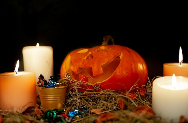 Calabazas y velas brillantes de Halloween en una mesa con una pajita