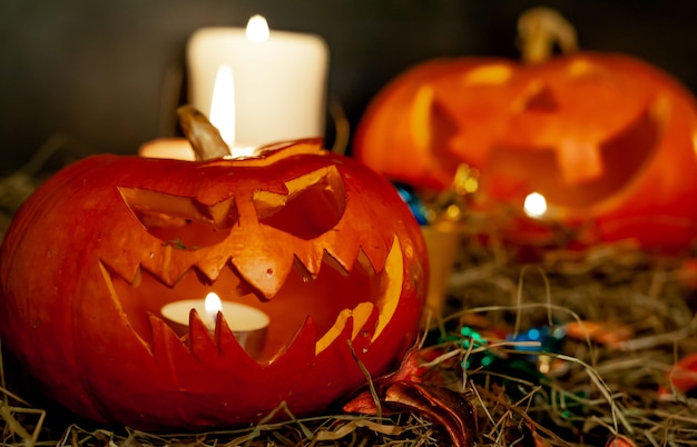 Calabazas y velas brillantes de Halloween en una mesa con una pajita