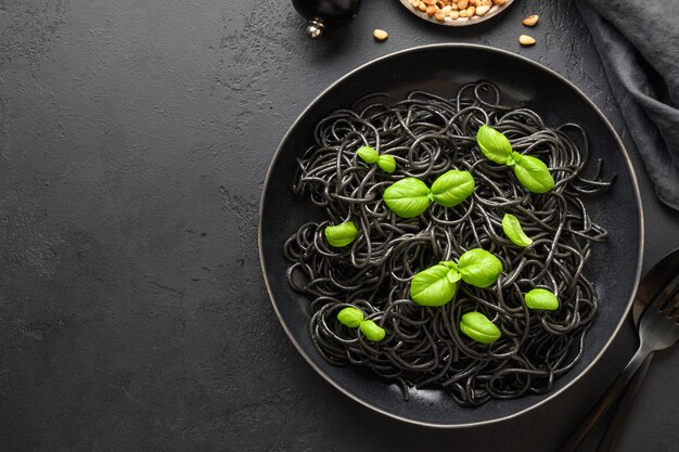 Calamar espagueti pasta negra Tinta con hojas de albahaca en un tazón.