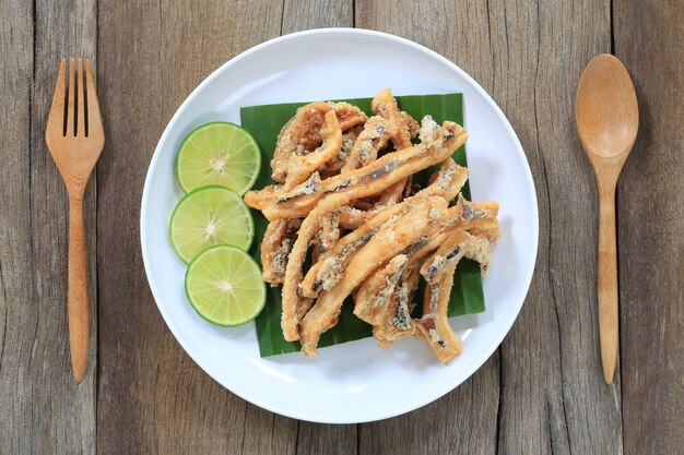 Calamar fritado de mariscos tailandeses no prato branco no assoalho de madeira.