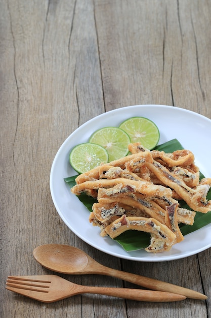 Calamar fritado de mariscos tailandeses no prato branco no assoalho de madeira.