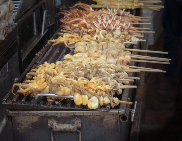 Calamares frescos en brochetas y asados al carbón. Mariscos listos para comer.