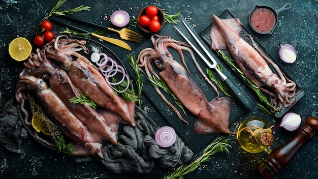 Calamares frescos con especias sobre un fondo de piedra oscura. Sobre un fondo oscuro.