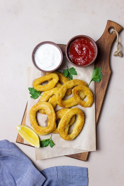 Calamares fritos con dos salsas, limón y hierbas. Comida rápida. Aperitivo.