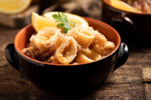 Calamares fritos italianos tradicionales y una rodaja de limón de cerca