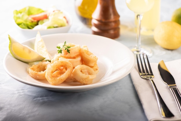 Calamares fritos italianos tradicionales y rodajas de limón servidos en un plato blanco