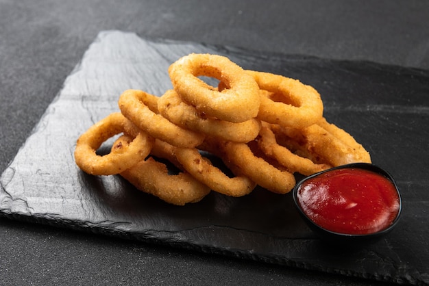 Calamari-Ringe frittiert in Panade knusprige Tintenfischringe auf dunklem Hintergrund mit Sauce