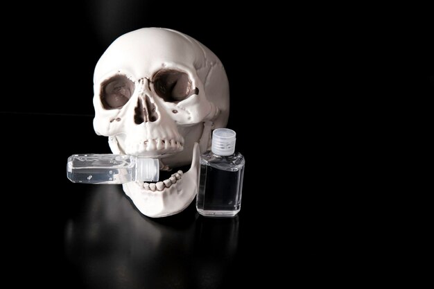 Calavera esquelética con botellas de desinfectante de manos para covid 19