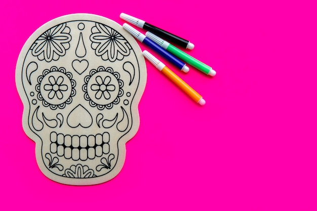 Calavera de madera para dibujar con rotuladores de colores sobre fondo rosa. Concepto de día de muertos. fiesta mexicana