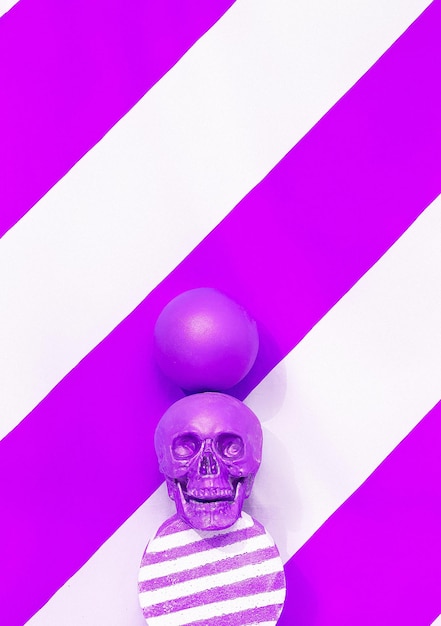 Calavera morada de moda y bolas en el espacio de geometría Vacaciones halloween Concepto de fiesta de año nuevo Escena minimalista de bodegones con estilo