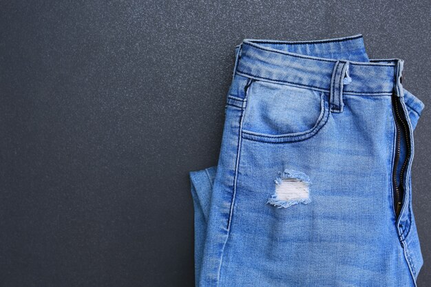 Calça jeans dobra no fundo escuro da telha. Roupas jeans com espaço de cópia