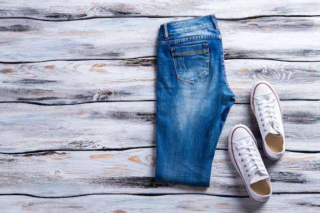 Calça jeans e keds brancos dobrados calças jeans e sapatos sapatos casuais no piso de madeira últimos itens em ...