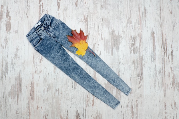 Calça jeans em uma madeira e folhas de plátano.