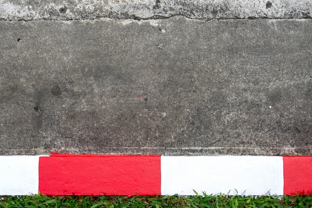 Calçada e estrada de asfalto com sinal de trânsito vermelho e branco (sem estacionamento)